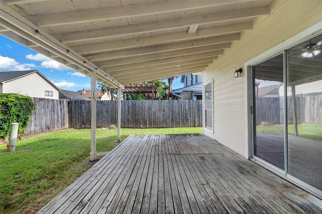 This additional view of the back patio also highlights the backyard, which is fully enclosed by a tall wooden fence for added privacy and security.