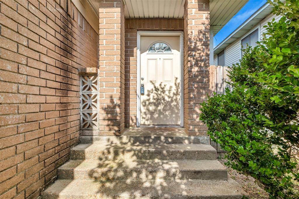 The home’s classic entrance features a brick wall and concrete steps leading up to the main door, creating a welcoming entryway.