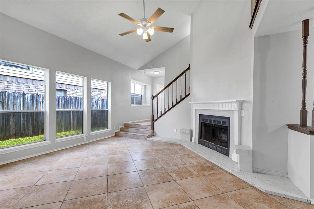 The living room features travertine tile flooring, large glass windows that let in plenty of natural light, and a fireplace for added warmth and comfort.