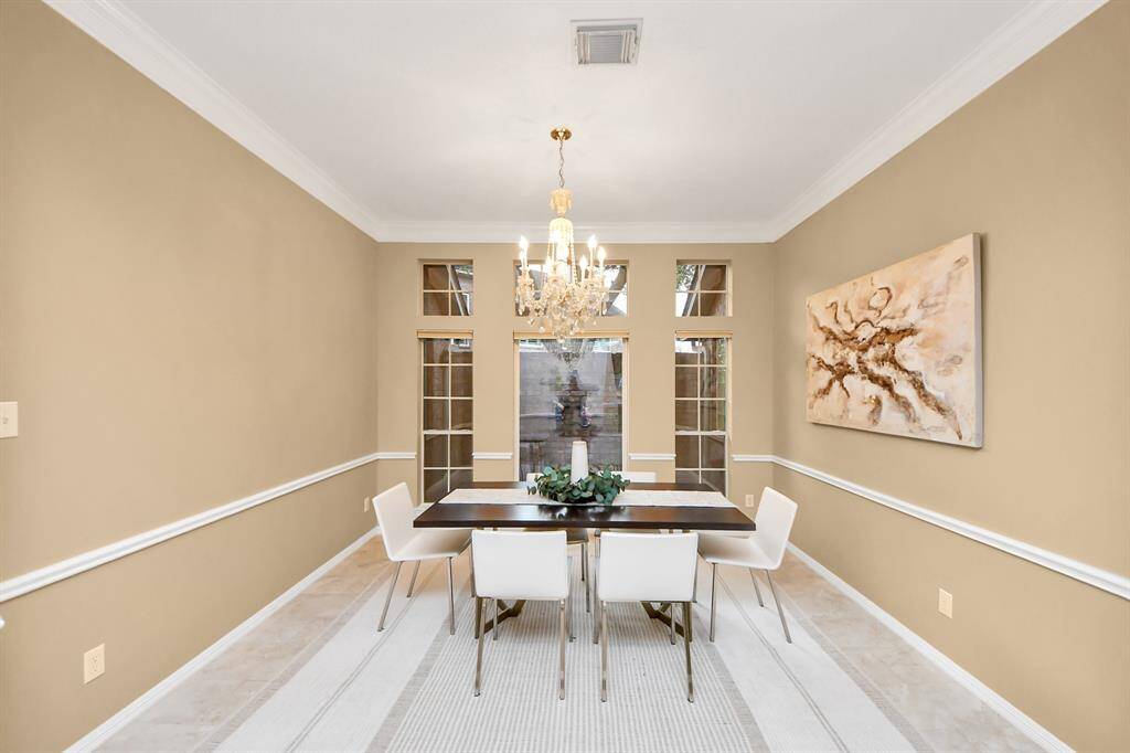 This elegant formal dining space is filled with natural light and also faces the small atrium, creating a bright and inviting atmosphere. The high ceilings and crown molding throughout add a touch of sophistication to the space.