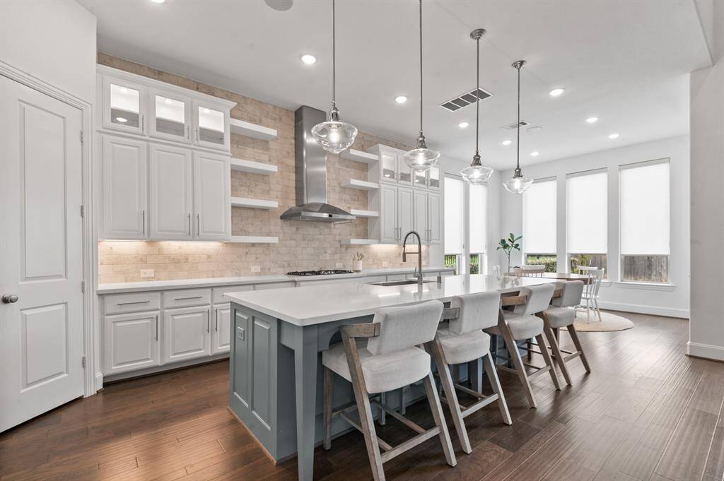 Gourmet kitchen featuring a huge island, sleek countertops, high-end appliances, ample storage, and floating shelves—designed for both function and style