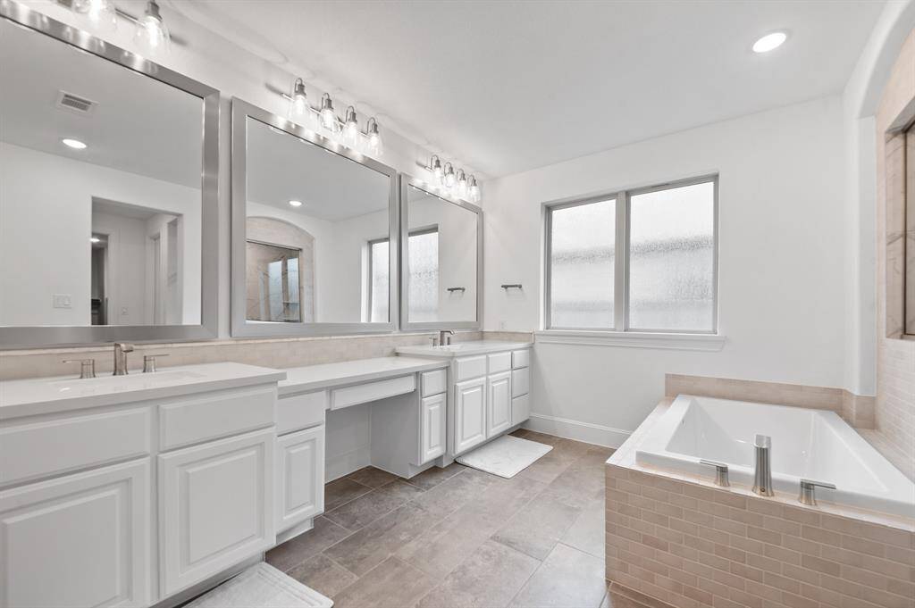 Luxurious primary bath featuring an extra-long vanity with dual sinks on each side and a spacious central vanity in between, offering ample counter space and a functional, stylish layout