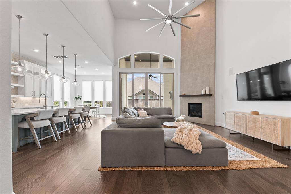 Grand living room with soaring ceilings, abundant natural light, and an open flow to the kitchen, creating a perfect space for entertaining and relaxation