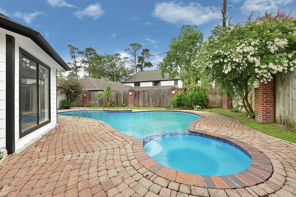 Backyard oasis with sparking pool, hot tube, and lush privacy landscaping.