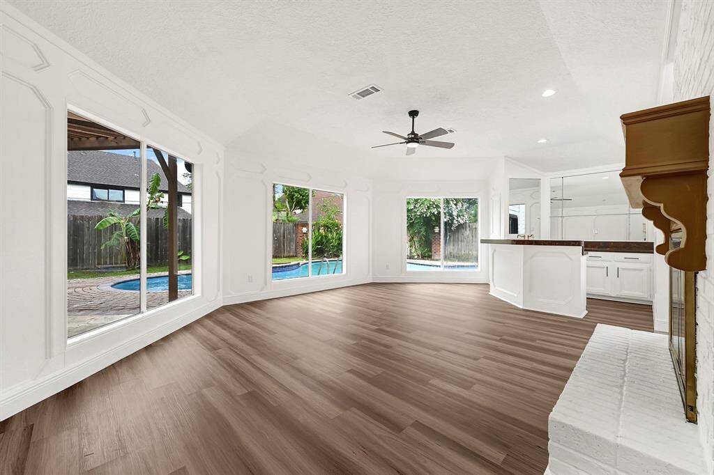 Open-concept family room with pool views, natural light, and seamless flow into the kitchen and backyard.