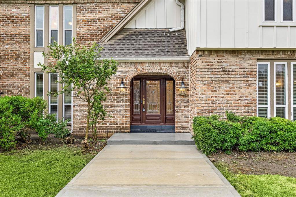A grand, oversized walkway leads from the street to a welcoming covered entryway, inviting guests in with style and shelter.