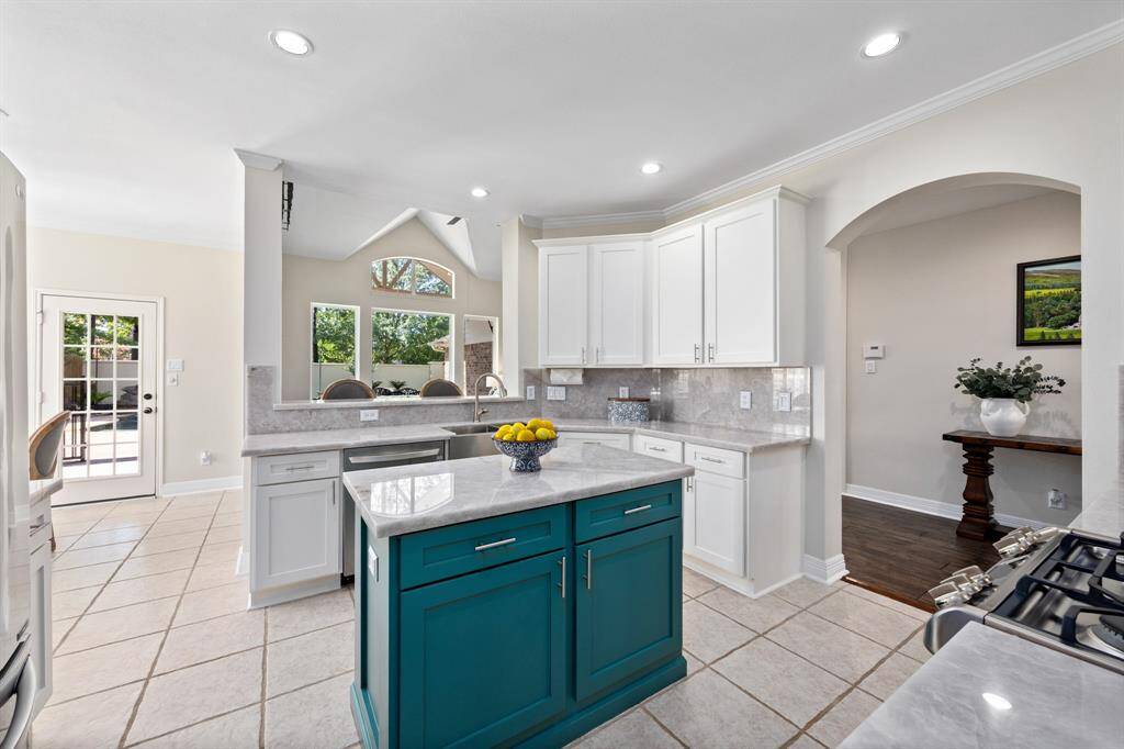 Stunning kitchen includes white cabinetry, illuminato quartzite counters and backsplash, and SS appliances.
