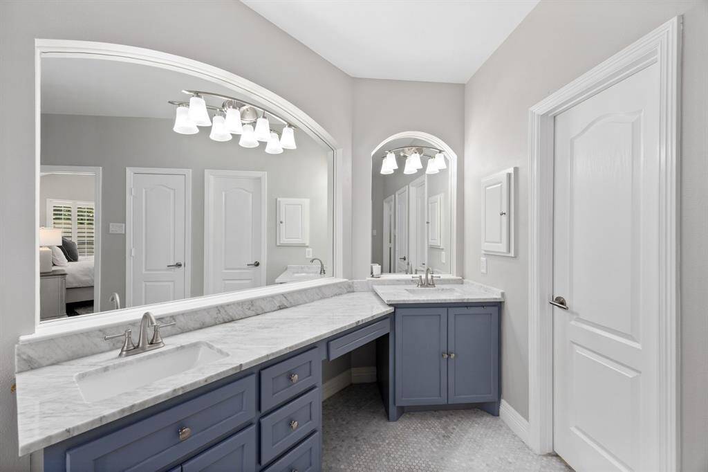 Custom clawfoot tub with vintage-inspired faucet, marble mosaic floors, marble subway tile, seamless glass shower, and marble-topped vanities.