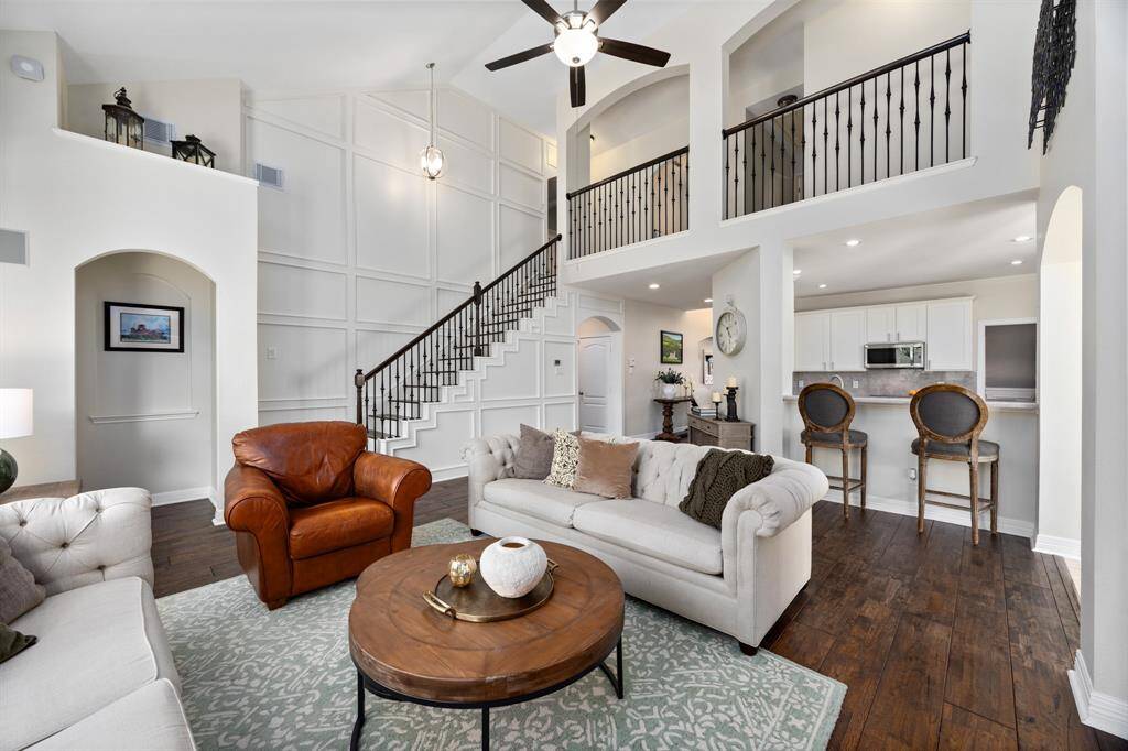 The open floorplan features soaring ceilings, custom built-ins, and a stunning custom millwork wall along the staircase.