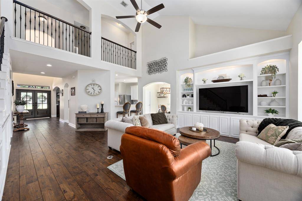 The open floorplan features soaring ceilings, custom built-ins, and a stunning custom millwork wall along the staircase.