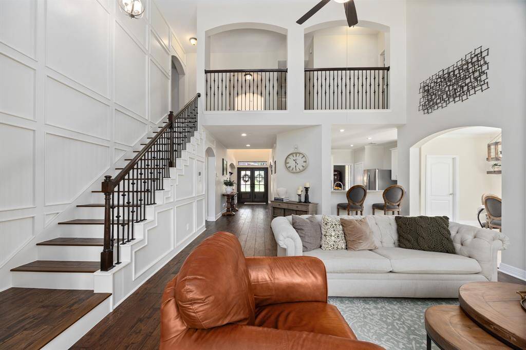 The open floorplan features soaring ceilings, custom built-ins, and a stunning custom millwork wall along the staircase.