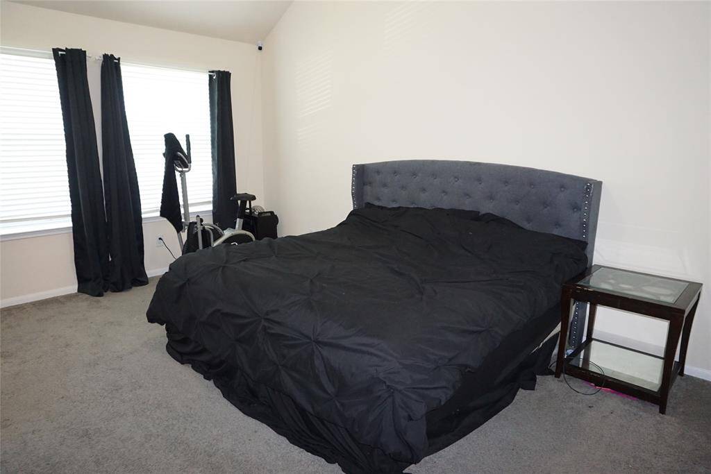 SPACIOUS Primary Bedroom with wall of windows with blinds and room darkening curtains.