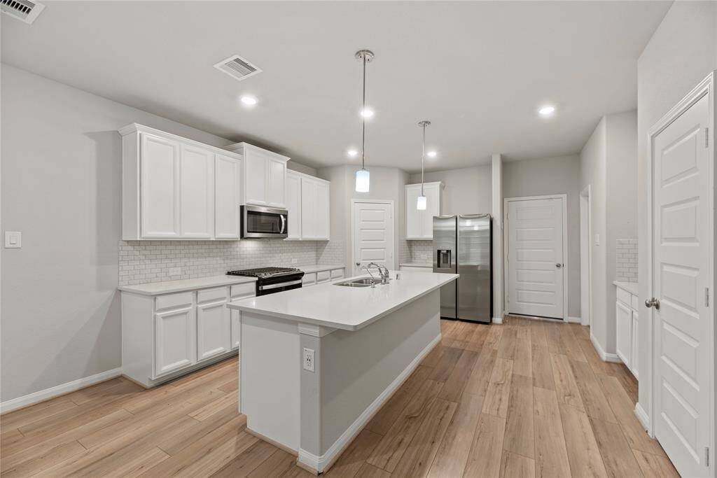 Your chef inspired kitchen awaits! Features include granite countertops paired with a coordinating tile backsplash, stainless steel appliances, crisp white cabinets, recessed and pendant lighting, and a sprawling island with breakfast bar seating.