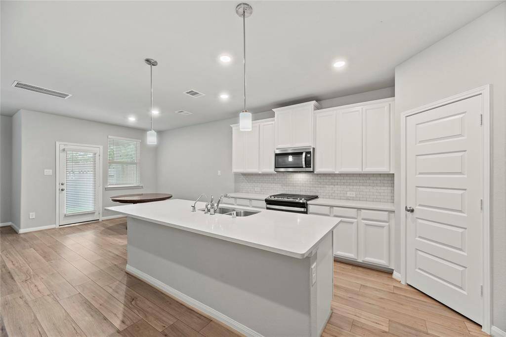 The sprawling island with breakfast bar seating serves as a versatile centerpiece, providing additional workspace, storage, and seating for casual dining or entertaining.