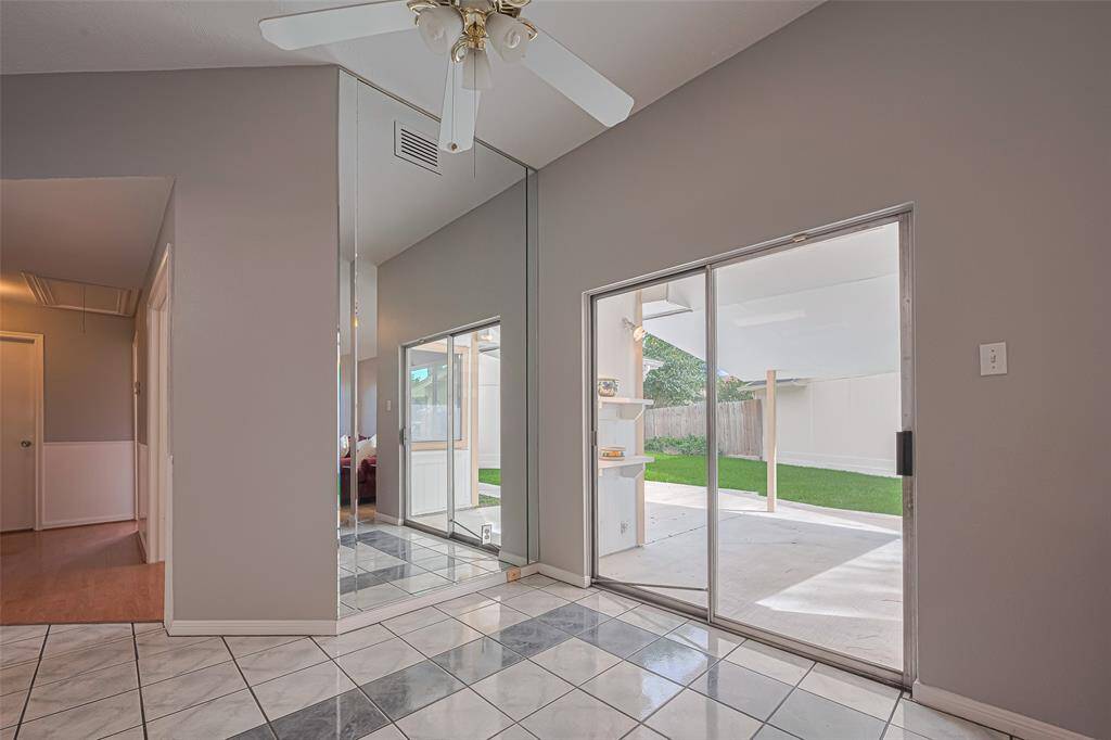 Set just behind the living space, the dining area feels open and welcoming, nestled beside sliding glass doors and a full-wall mirror that doubles the light and sense of space.
