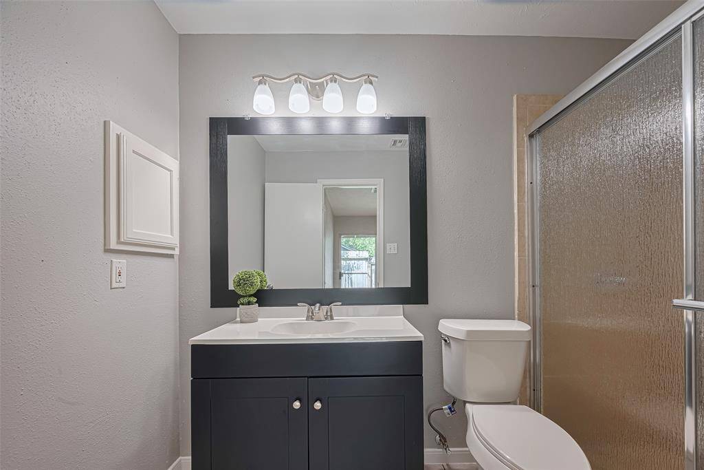 With clean lines and contrasting finishes, this bathroom features a black-and-white vanity and a fully enclosed shower—streamlined and efficient.