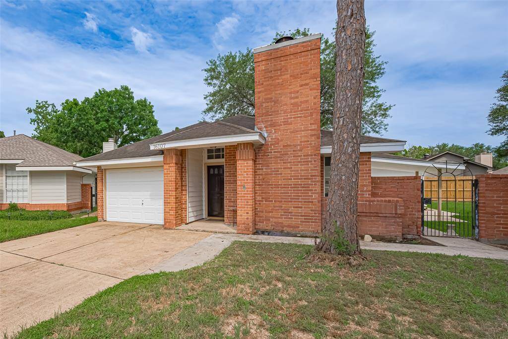 Classic brickwork extends to the side, where a black iron gate opens to the backyard—both functional and quietly elegant.