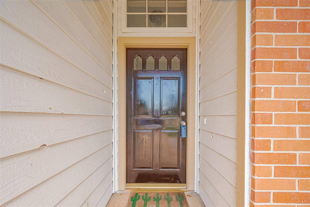 Tucked into a recessed alcove, the front door sits beneath a transom window, offering soft, natural illumination as you enter the home.