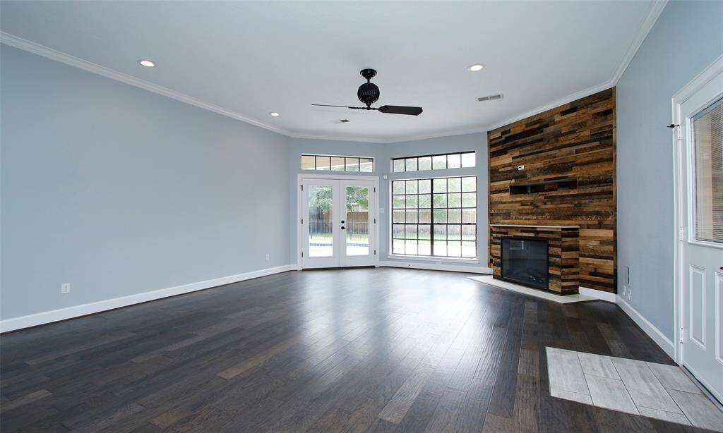 n additional view of the family room highlights a double glass door leading to the backyard, complemented by expansive windows that flood the space with natural light.