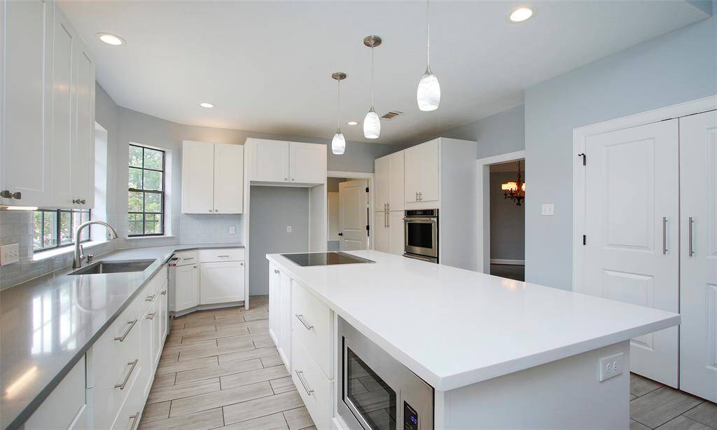 The kitchen features a stylish island, beautifully complemented by elegant drop lights overhead, adding both function and charm to the space.