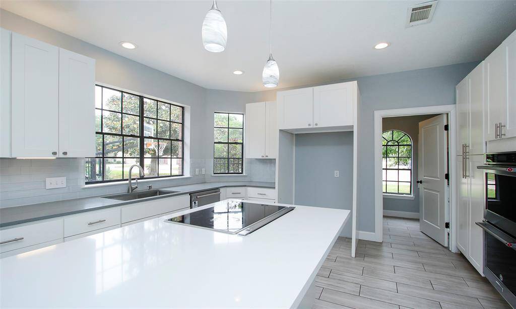 The white cabinetry and countertops beautifully complement the soft powder blue walls, creating a fresh and inviting kitchen atmosphere.