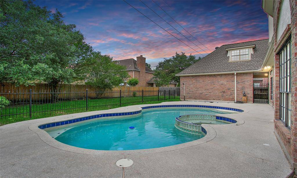 The swimming pool is beautifully set on the concrete patio.
