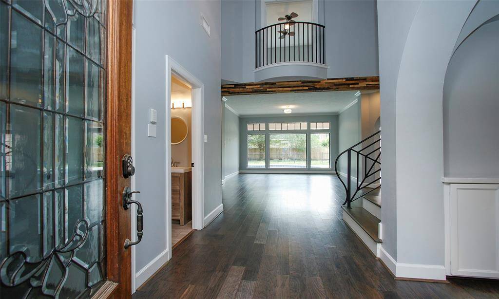 A partial view from the main door reveals a welcoming hallway, a staircase leading to the second floor, and a door to a convenient half bath.
