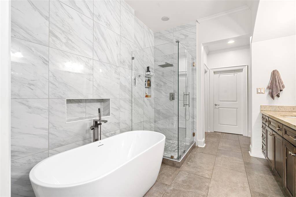 Primary bathroom, recently remodeled with freestanding tub, new tile, and frameless glass shower enclosure