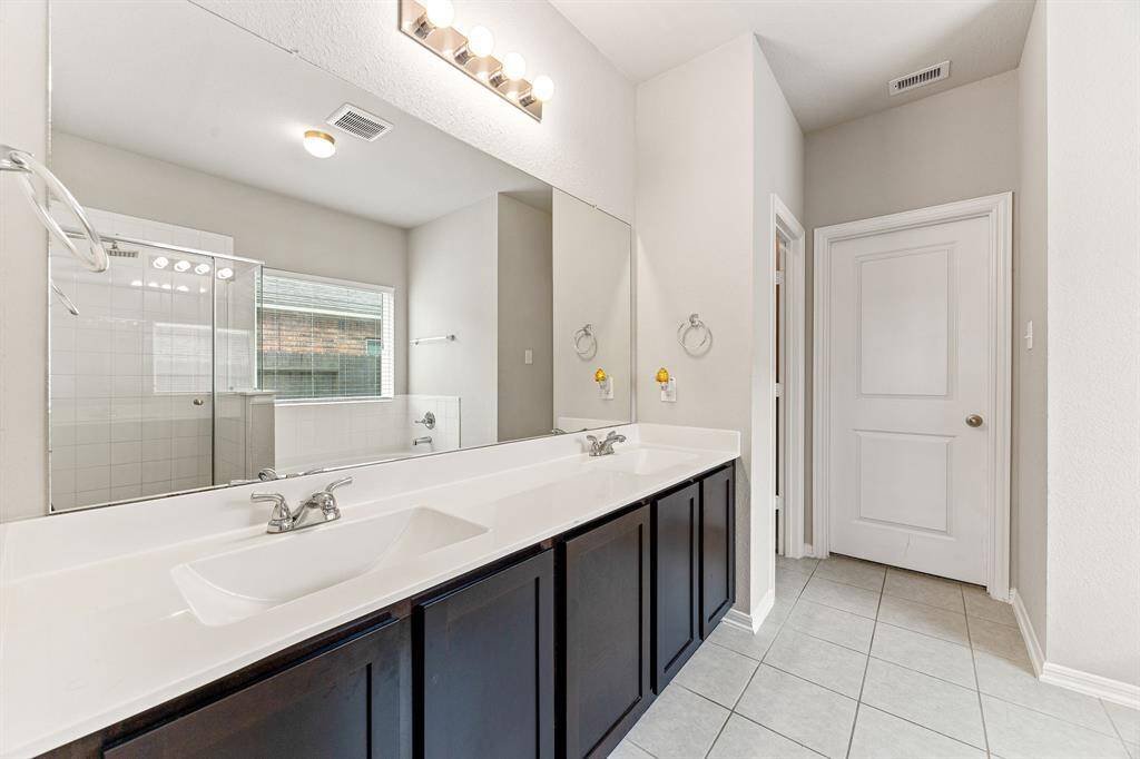 This primary bathroom is definitely move-in ready! Featuring a framed walk-in shower with tile surround, separate garden tub for soaking after a long day with custom tile detailing, dark stained cabinets with light countertops, spacious walk-in closet with shelving, high ceilings, custom paint, sleek and dark modern finishes.