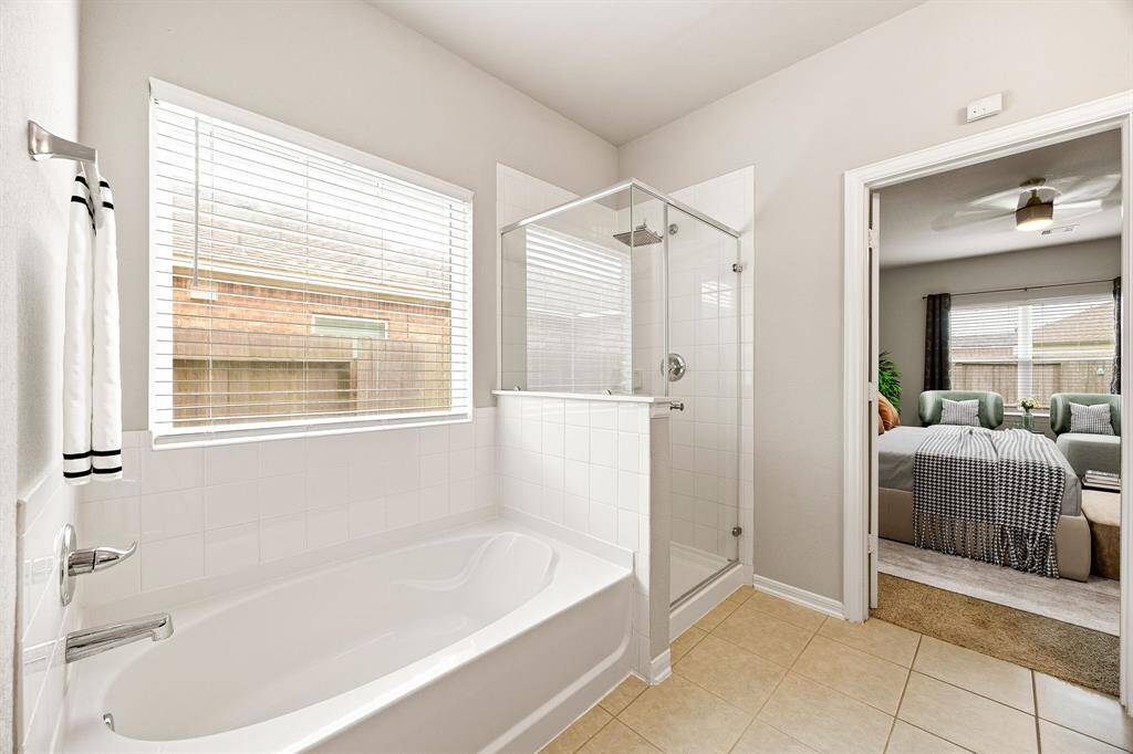 This additional view of the primary bath showcases a walk-in shower with tile surround and a separate garden tub perfect for soaking after a long day.