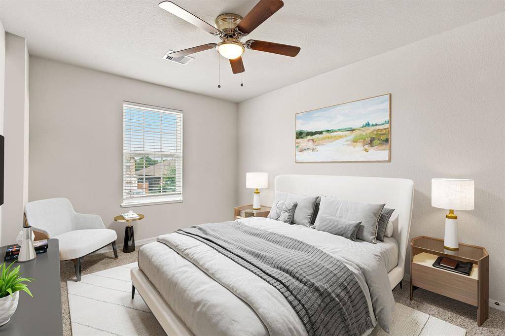 Secondary bedroom features plush carpet, custom paint, dark stained ceiling fan with lighting and a large window with privacy blinds. *Virtually Staged