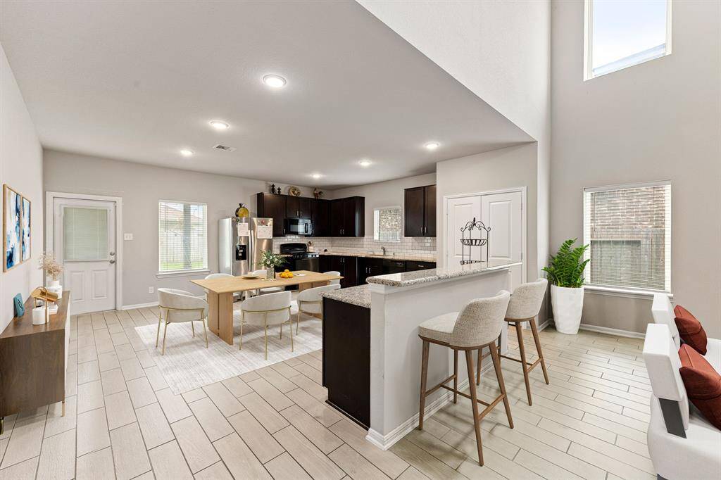 This stunning kitchen displays such a beautiful contrast with the dark stained cabinets, custom neutral paint, granite countertops, light modern backsplash, and SS appliances, oversized kitchen island with extra storage, breakfast bar, recessed lighting, high ceilings and walk in pantry. *Virtually Staged