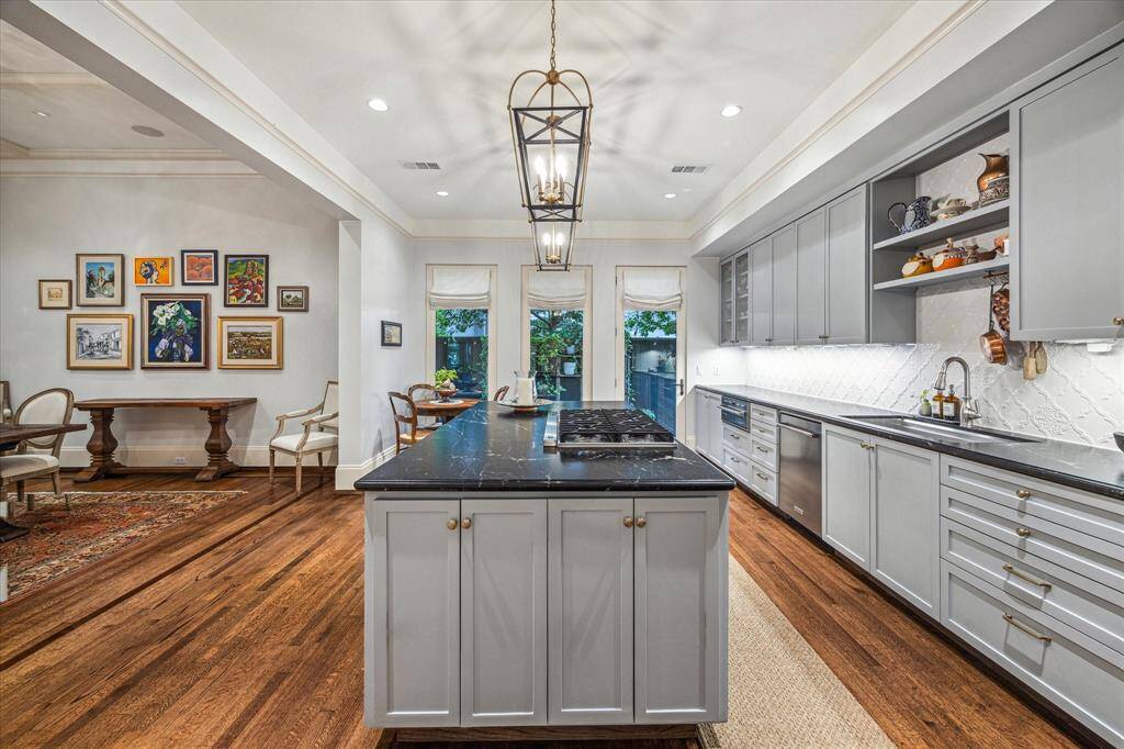 A chef’s dream: this beautifully appointed kitchen features soft-gray cabinetry, leathered granite countertops, a wine fridge, stainless steel appliances, and a generous island.