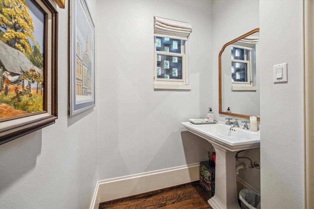 Charming and classic, the powder bath features a pedestal sink and hardwood floors.