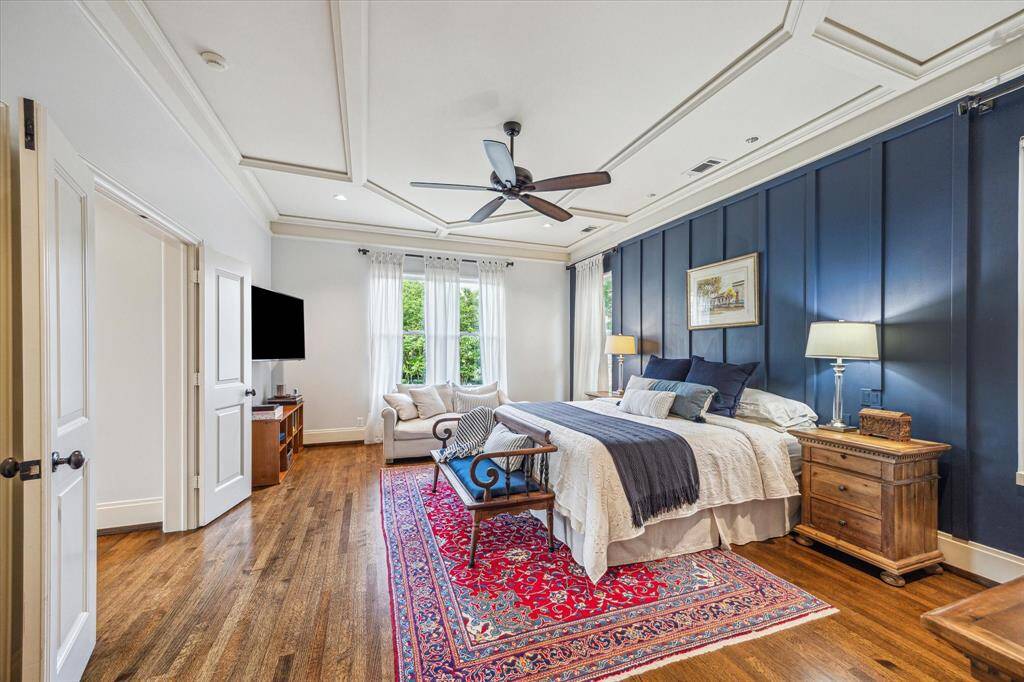A serene retreat with custom millwork, deep navy accent wall, and coffered ceiling—offering space to unwind with abundant natural light and a cozy seating nook.