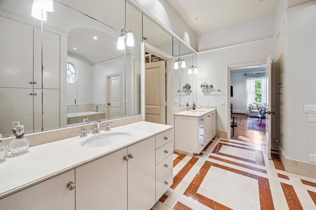 Elegant and functional, the primary suite bath features high ceilings, intricate tilework, and symmetrical vanities for a clean, calming aesthetic.
