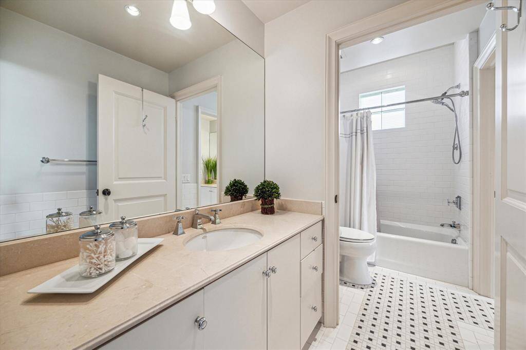Hollywood bathroom with sconce lighting, granite countertop and access to a shared water closet with a shower/tub combo.