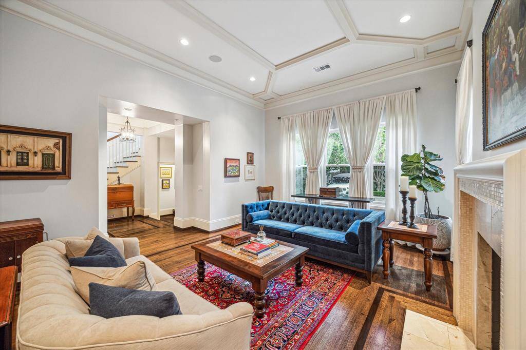 Living room with coffered ceilings, rich hardwood floors, and a marble fireplace.
