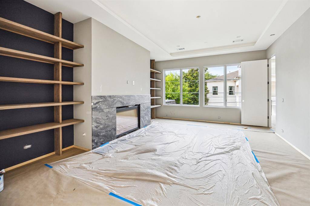 Primary Bedroom with a Coffered Ceiling, Stained Grade Wood Shelving, and Fireplace with Marble Surround