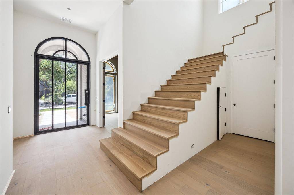 Entrance with a Steel Front Pivot Door. Open Staircase with Oval Spindles & Flat Steel Handrail.