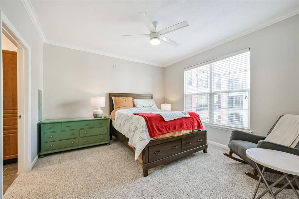 Bedroom features plush carpet, ceiling fan and elegant crown molding.