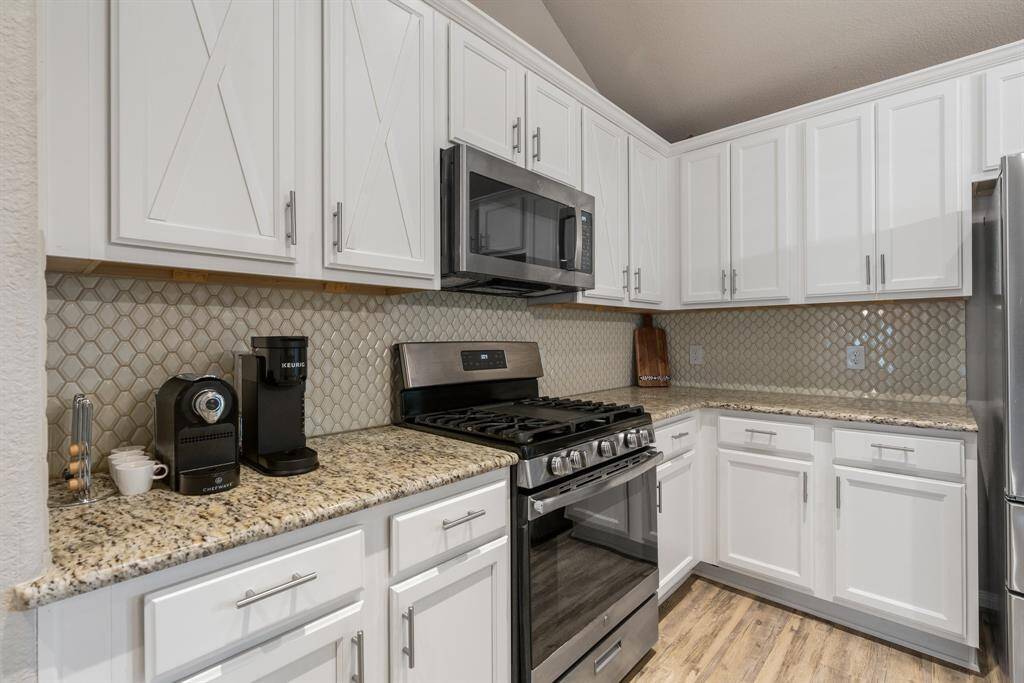 Kitchen features modern white cabinetry with sleek hardware, granite countertops, and a stylish backsplash.