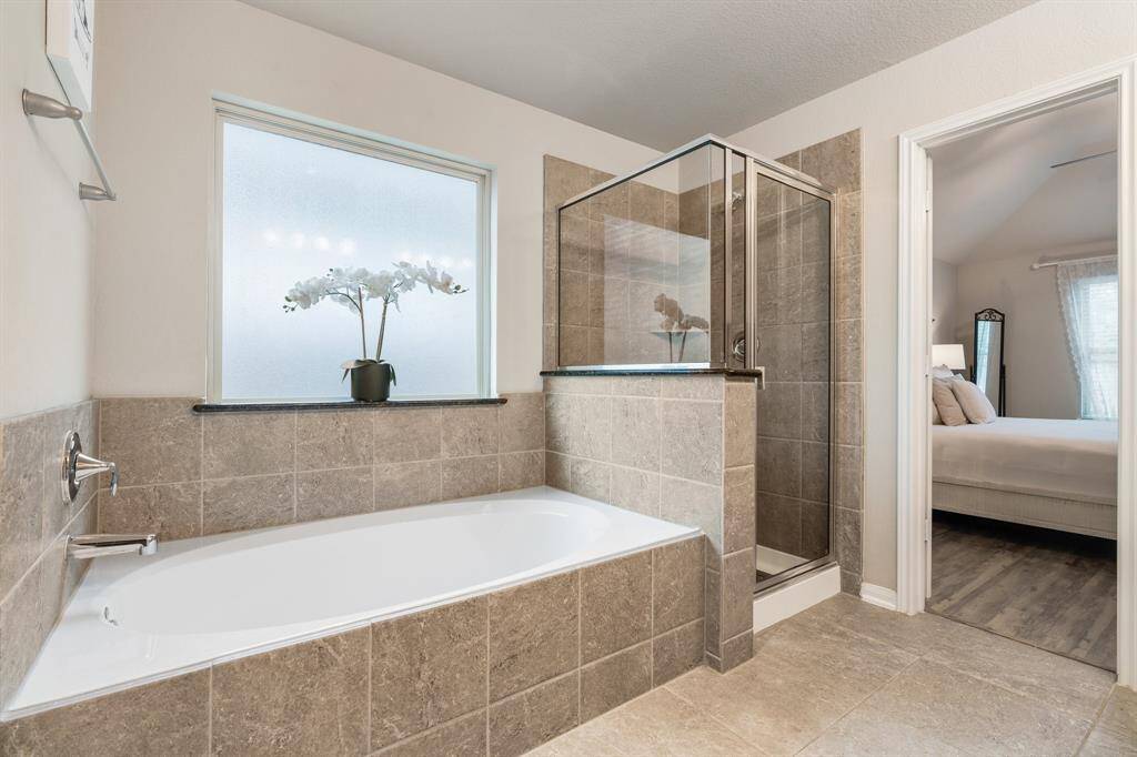 features a spacious design with a tiled bathtub. Natural light enhances the space through a frosted window.
