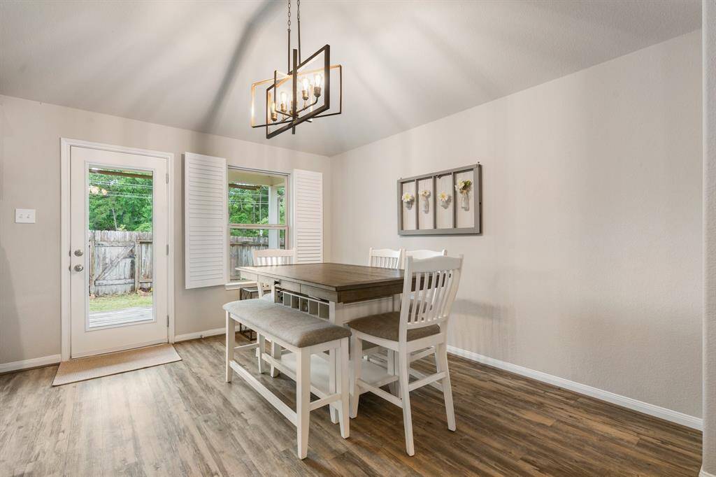 This dining area features a modern chandelier and a view of the backyard through glass doors, creating a bright and inviting space.