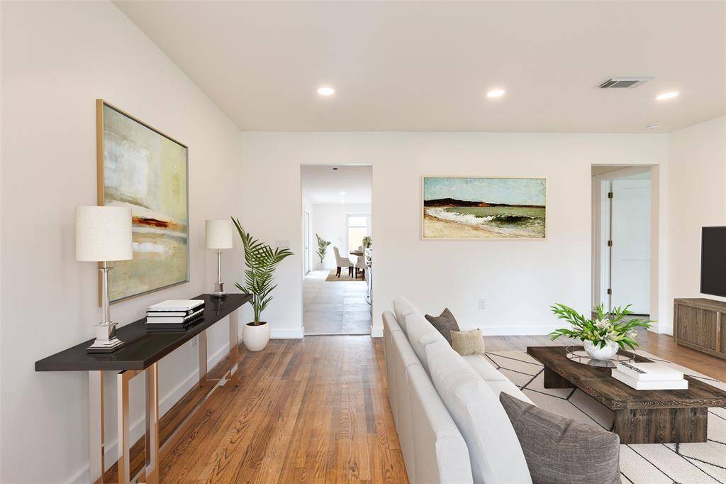Virtually staged to feature a cozy seating area, stylish coffee table, and a glimpse into the dining area through an open doorway.