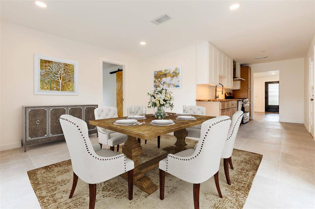 This virtually staged dining room showcases a modern dining area with a wooden table, elegant white chairs, and tasteful decor. The open layout connects to a contemporary kitchen with ample cabinetry. Soft lighting and neutral tones create a warm, inviting atmosphere.