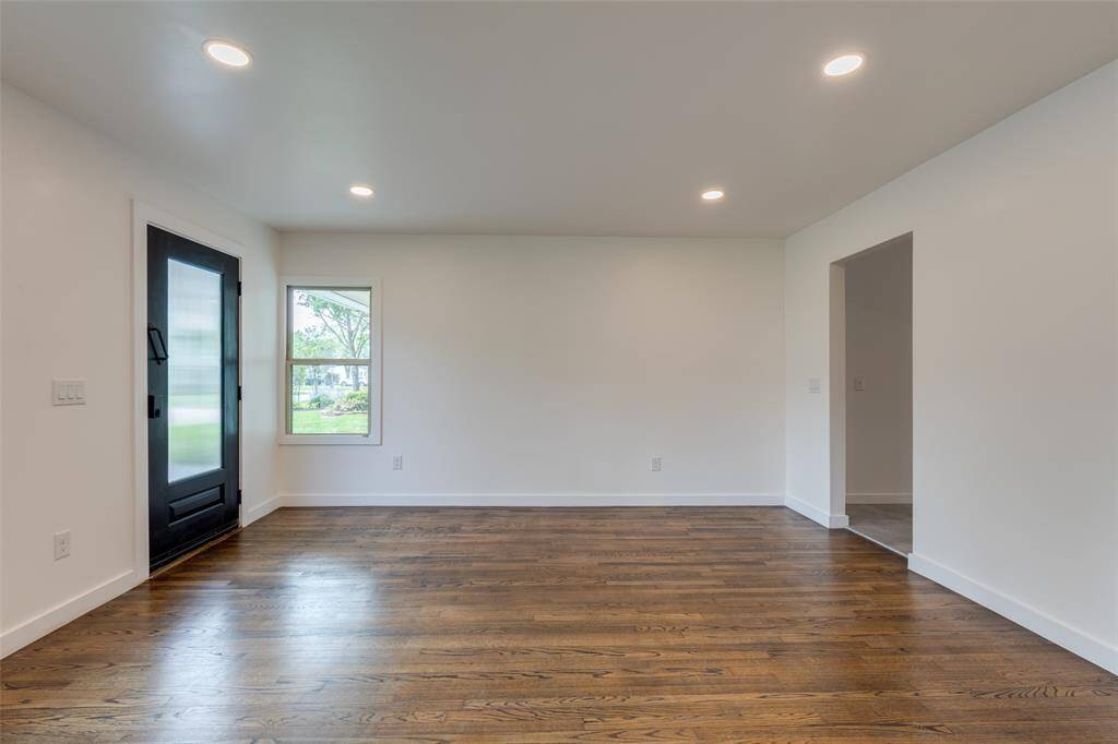 Bright, open living space with original hardwood floors, recessed lighting, and large windows for natural light.
