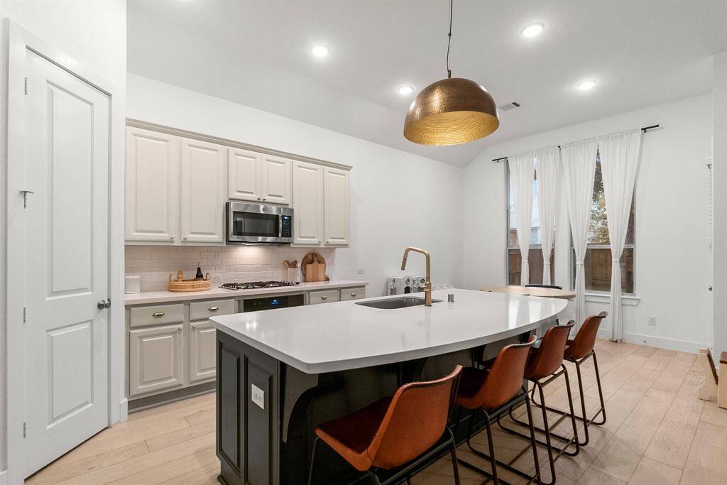 This gourmet kitchen is the heart of this fine home and is complete with large curved island for extra storage and workspace,  breakfast bar seating, exotic quartz counter tops, 6-inch baseboards, and wood plank flooring. Meticulous chefs will also demand such features as recessed lighting to enhance workspace, a deep single basin sink, and spacious storage in the 42" upper cabinetry. This Kitchen has it all!