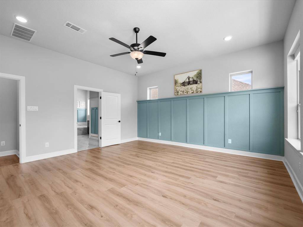 In the Primary Suite tucked away from the other bedrooms, you're greeted with tall ceilings, board & batten wall & tons of cross lighting.