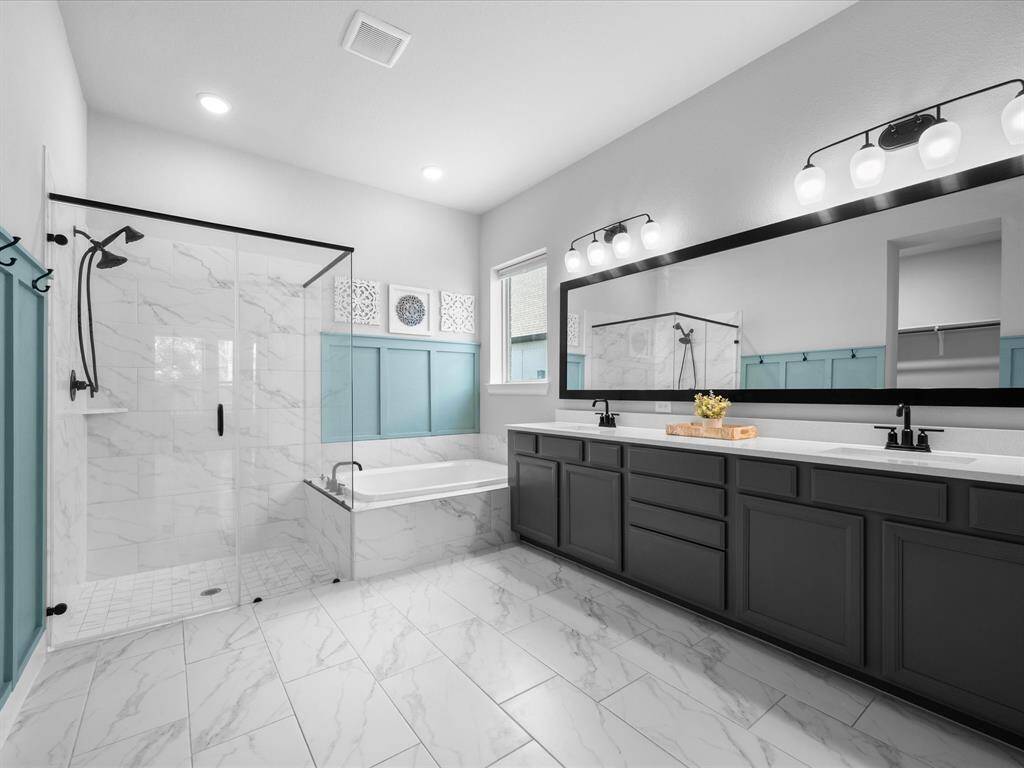Luxury Primary Bathroom awaits you with frameless Walk-In Shower with tile flooring, large soaking tub, Quartz Countertops & dual sinks.